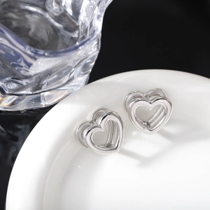 Vista macro degli orecchini a cuore cavo a doppio strato in argento lucido su ceramica