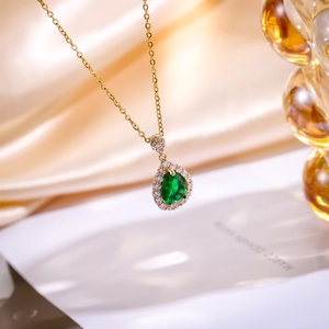 Detailed close-up of water drop green zircon pendant on a gold titanium steel necklace