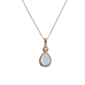 Macro shot of rose gold waterdrop pendant with translucent jade-like stone and pavé diamonds