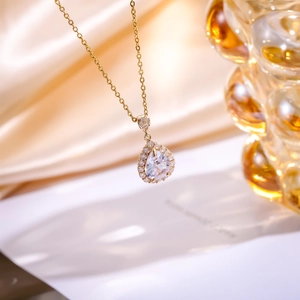 Detail shot of pear-cut zircon teardrop necklace with small stones on champagne satin