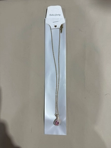 Detail view of pink teardrop pendant with small diamonds on a gold titanium steel chain