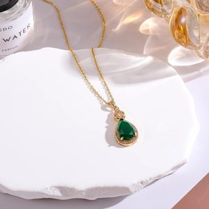 Macro detail of teardrop green gemstone pendant with pavé diamonds on stone base