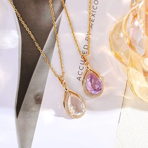 Dettaglio di collane placcate oro con pendenti a goccia in zircone viola e trasparente