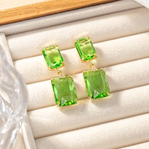 Macro view of tiered emerald green crystal earrings with elegant gold-plated claw setting