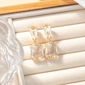 Detail view of pear and emerald cut crystal earrings on a velvet jewelry display
