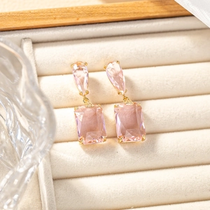 Macro detail of pink rectangular and pear cut crystal drop earrings on velvet