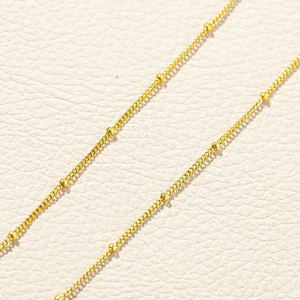 Macro shot of 18k gold plated satellite chain detail on textured leather background
