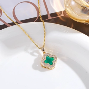 Detailed close-up of a gold clover necklace with green stone and pavé diamond border