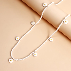 Détail de la chaîne de taille perlée blanche avec petits pendentifs marguerites sur socle