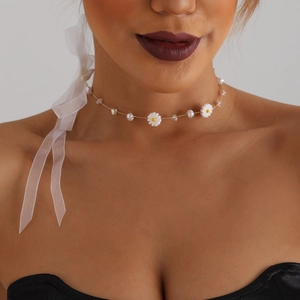 Detail eines Gold-Chokers mit weißen Gänseblümchen, Perlen und Kristallen am Model