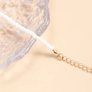 Détail de la chaîne de taille en perles blanches avec fermoir mousqueton doré et extension