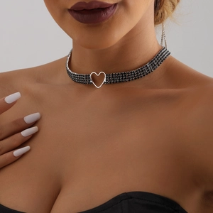 Detail eines mehrlagigen schwarzen Strass-Chokers mit einem silbernen hohlen Herzanhänger