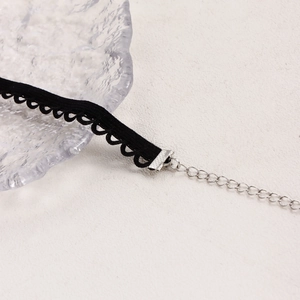 Detalle de gargantilla gótica de encaje negro con diseño ondulado y cierre de metal plateado