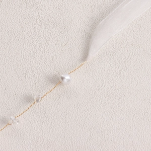 Makroaufnahme der Braut-Schleifenkette mit Golddraht, weißen Perlen und Kristallen