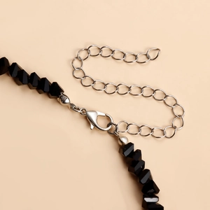 Detail van de zwarte kralenketting met zilveren karabijnsluiting en verstelbare verlengketting