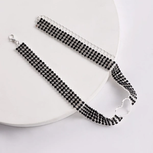 Detail eines vierreihigen schwarzen Strass-Chokers mit silbernem hohlem Herzanhänger