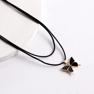 Détail du pendentif papillon doré avec incrustation noire et cordon en velours doux