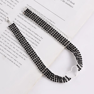 Makro-Detail des mehrreihigen schwarzen Strass-Chokers mit silbernem Herzanhänger