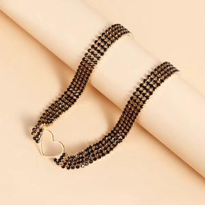 Detailed macro of a multi-layer black rhinestone choker with a golden heart pendant