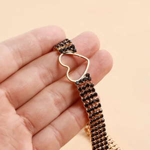 Close-up of golden multi-layer necklace featuring black crystals and hollow heart design