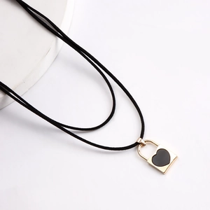 Detalle del colgante de candado dorado con corazón negro y cordón doble de terciopelo