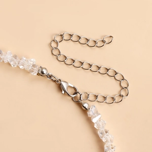 Detail van zilveren karabijnsluiting en verlengketting op kralenketting met kristal
