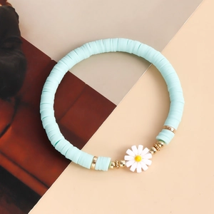 Detail of light blue Heishi clay bead bracelet with a small white daisy pendant and gold beads