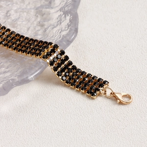 Detailed macro view of gold-plated multi-layer necklace with black claw-set rhinestones