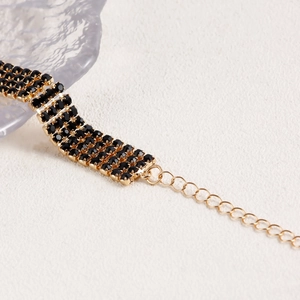 Close-up of four-row black rhinestone chain with golden adjustable lobster clasp closure