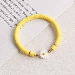 Close-up of yellow polymer clay bead bracelet with daisy pendant on magazine background