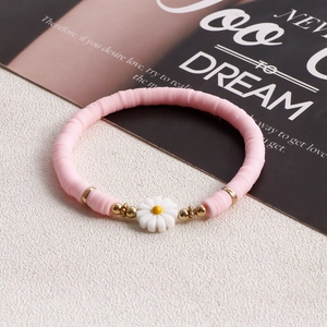 Close-up of pink Heishi bead bracelet with a white daisy charm and gold metal accents