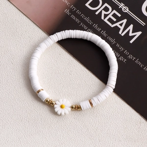 Detailed close-up of white heishi bead bracelet with daisy charm and gold metal accents