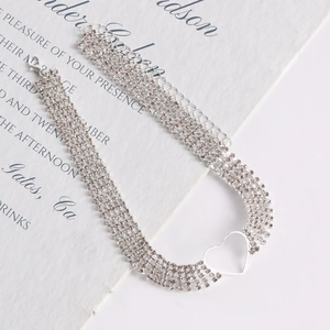 Macro shot of silver multi-row choker featuring four rows of rhinestones and a hollow heart pendant