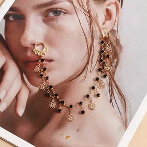 Detailed view of bohemian gold nose-to-ear chain with black beads and floral charms
