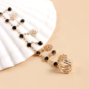 Golden ethnic ear-to-nose chain with black crystals and floral charms on white shell