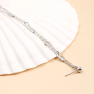 Detail showing the silver chain earring with cylindrical beads and a smooth metallic finish