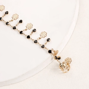 Detail of bohemian gold chain nose ring with black crystal beads and flower accents