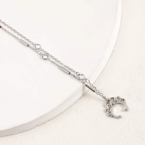 Detail of silver double chain necklace featuring crown pendant and faux diamond accents