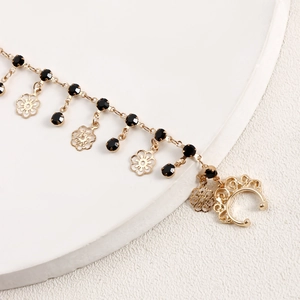 Detail of gold metal nose chain with black faceted beads and hollow flower charms