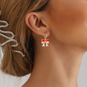 Elegant gold-tone alloy bow earrings with red enamel on female model for a chic style