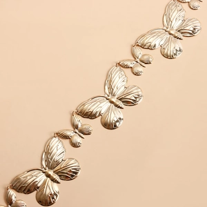 Détail macro de la chaîne de taille papillon dorée avec textures d'ailes et fini miroir