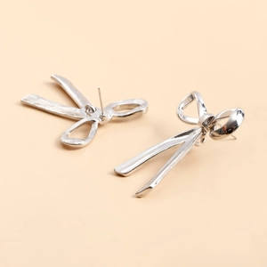 Detailed view of silver bow ribbon earrings featuring polished metal and stud backing