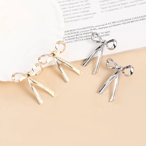 Detail view of gold and silver bow-shaped drop earrings set on a minimalist background