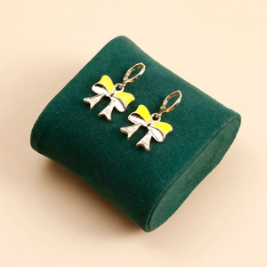Fashionable gold alloy bow earrings with yellow and pearl white enamel on display stand
