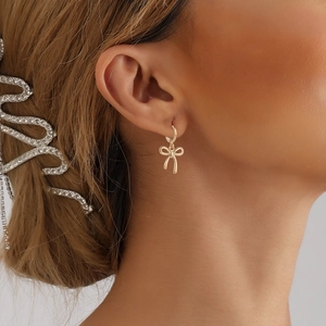 Boucles d'oreilles pendantes en forme de nœud doré élégant sur mannequin femme