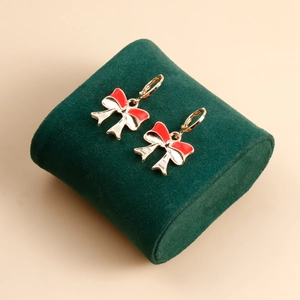 Detail of gold bow earrings with red and white enamel on a green pedestal display