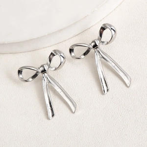 Macro shot of silver bow knot drop earrings with polished metallic ribbon details