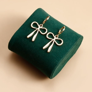 Vue macro de boucles d'oreilles nœud dorées sur coussin de velours vert avec éclat poli