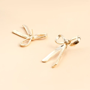 Detail view of elegant golden bow stud earrings with a glossy metallic finish