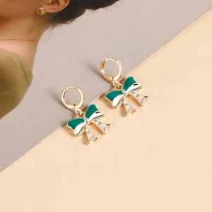 Detailed close-up of vintage gold bow earrings with dark green and white enamel finish